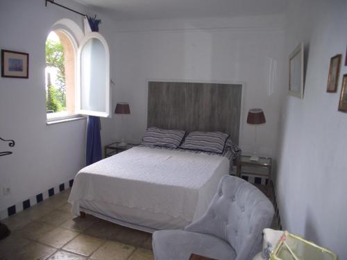 a bedroom with a bed and a chair and a window at soleil et farniente in Cervione