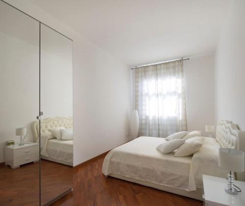 a white bedroom with two beds and a mirror at Modern sunny apartment in residental area in Venice