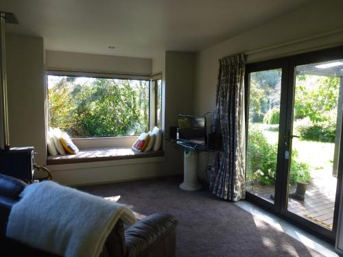 a living room with a large window and a couch at Idyllic Country Garden in Manakau