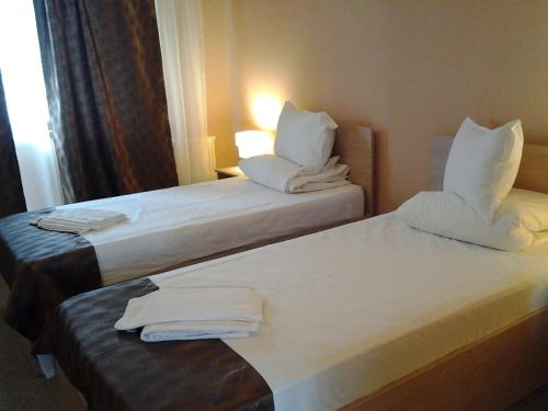 two beds in a hotel room with white pillows at Hostel Nova Route in Mamaia Sat/Năvodari