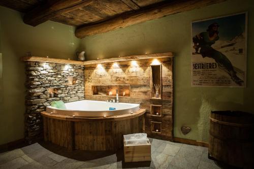 ein Badezimmer mit einer Badewanne und einer Steinmauer in der Unterkunft Lous Escartoun in Pragelato