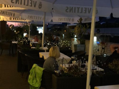 a woman sitting at a table in a restaurant at night at Hotel & Restaurant Blume in Wolfsburg
