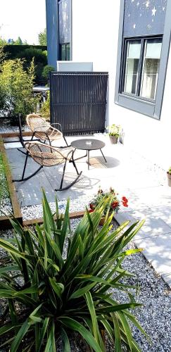 a patio with two chairs and a table and a plant at Logis Boutique Hotel Novalis in Gradignan