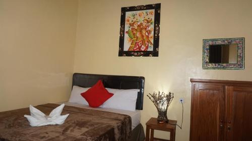 a bedroom with a bed with red pillows and a mirror at Bima Sakti Homestay Echo Beach Canggu in Canggu