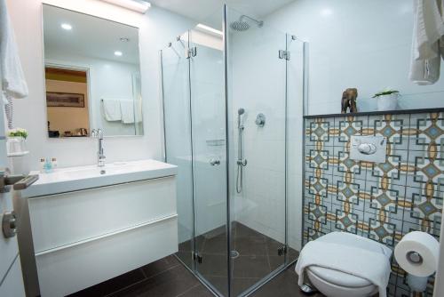 a bathroom with a shower and a toilet and a sink at Out of Africa Resort in Had Nes