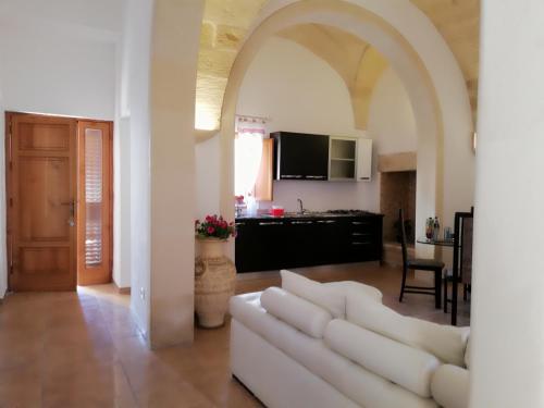 a living room with a white couch and a kitchen at Dimora Cinzia in Uggiano la Chiesa