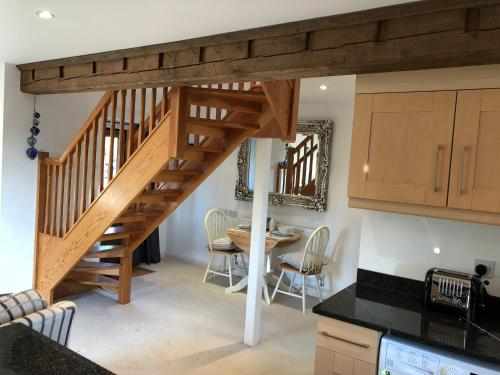 a kitchen and dining room with a wooden staircase at The Stable Barn *On the edge of the New Forest* in Downton