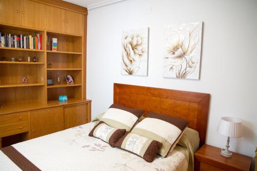 a bedroom with a bed with two paintings on the wall at Apartamento Garcilaso de la Vega in Cuenca