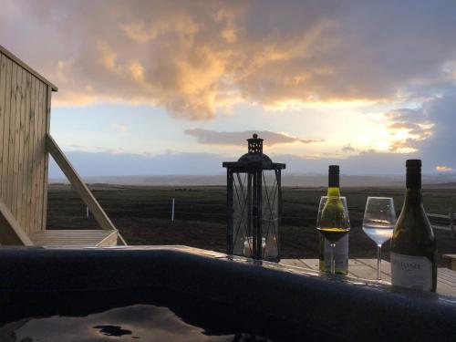 two bottles and two glasses of wine sitting on a bath tub at Akurgerði Guesthouse 6 - Country Life Style in Ölfus