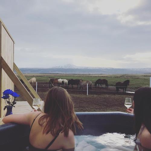 a woman in a hot tub looking at horses at Akurgerði Guesthouse 8 - Country Life Style in Ölfus