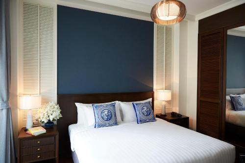 a bedroom with a bed with blue and white pillows at The Rose Residence, Bangkok in Bangkok