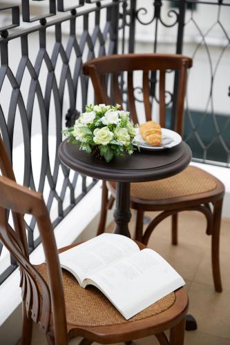 a table with a plate of flowers and a book at The Rose Residence, Bangkok in Bangkok