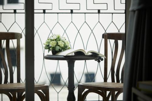 a table with a vase of flowers and two chairs at The Rose Residence, Bangkok in Bangkok