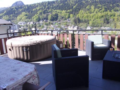 a balcony with a table and chairs and a large tub at chez Andréa in Le Mont-Dore