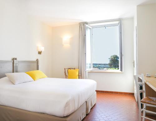 - une chambre avec un grand lit blanc et une fenêtre dans l'établissement Hotel La Bienvenue, à La Croix-Valmer