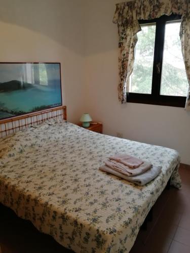 a bedroom with a bed with a blanket and a window at La Lantana Nuova in Flumini di Quartu