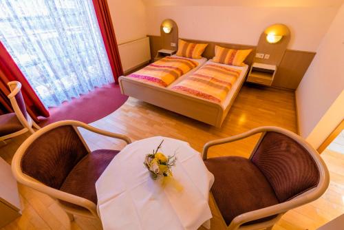 a room with a bed and two chairs and a table at Gästehaus Sonne in Gernsbach