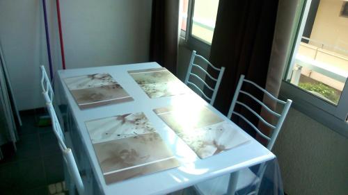 une table blanche avec des images dessus à côté d'une fenêtre dans l'établissement 6 Rue du Labech, au Cap d'Agde