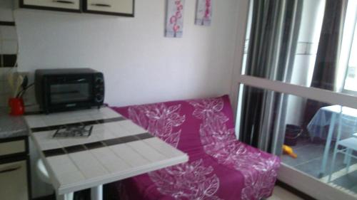 - un salon avec un canapé violet et un four micro-ondes dans l'établissement 6 Rue du Labech, au Cap d'Agde