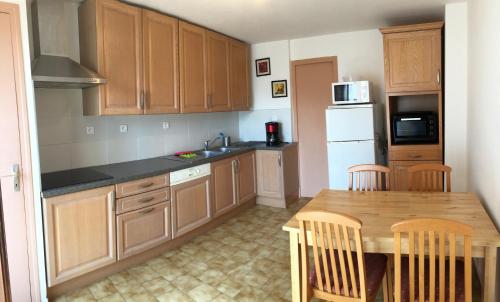 a kitchen with wooden cabinets and a table with chairs at Cairenou Location in Saint-Martin-dʼArdèche