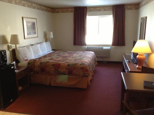 um quarto de hotel com uma cama e uma janela em Royal Inn Airport Salt Lake City em Salt Lake City