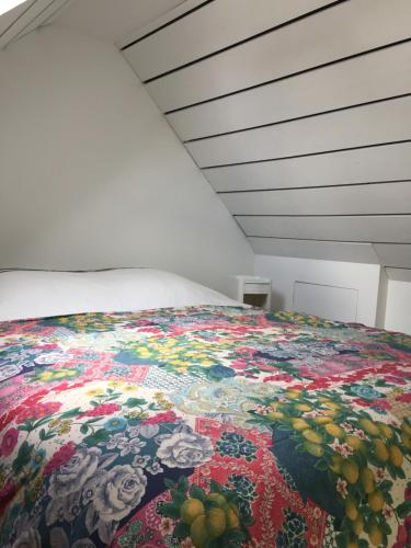 a bed with a colorful blanket on it in a room at Le Gîte "Le Grand Chêne" in Le Cloître-Saint-Thégonnec