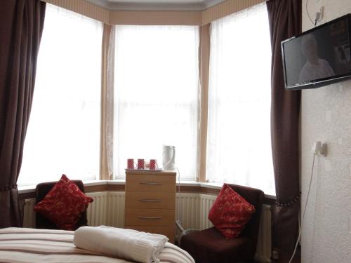 a bedroom with a bed and a tv and windows at Jasmine Guest House in Bridlington