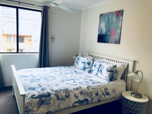 sypialnia z łóżkiem z niebiesko-białą pościelą i oknem w obiekcie Inner City Apartments Hotel w mieście Perth