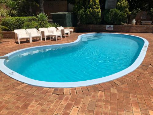 a large swimming pool with chairs in a yard at Wheeler Apartments Perth in Perth