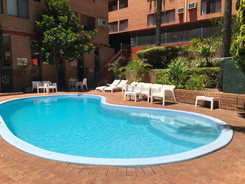 a large swimming pool with chairs and a building at Wheeler Apartments Perth in Perth