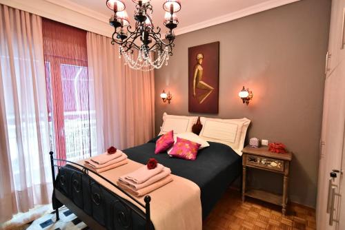 - une chambre avec un lit et un lustre dans l'établissement Queens Bed&Rest Luxury Apartment, à Kavala