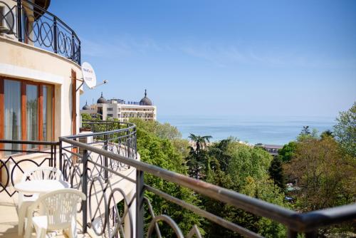 uma varanda com cadeiras brancas e vista para o oceano em Sea View Rental Iglika Apartments em Golden Sands