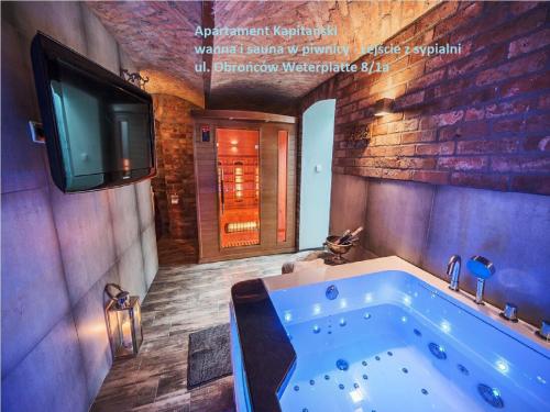a bathroom with a tub with a tv on the wall at Sopot Spa Apartament in Sopot
