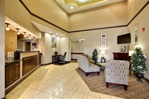 a lobby with a waiting area with chairs and a tv at Magnolia Inn and Suites Pooler in Savannah