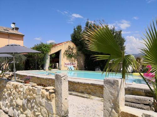 - une piscine avec un parasol en face d'une maison dans l'établissement Maison d'Anvers, à Valréas