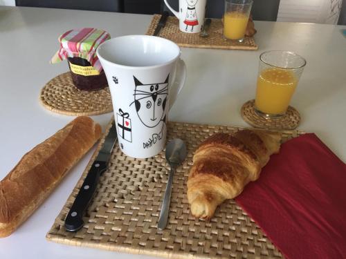 une table avec du pain et une tasse de jus d'orange dans l'établissement Camping La Pindière, à Héric