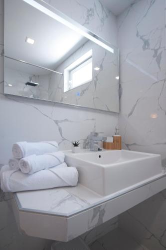a white bathroom with a sink and a mirror at Apartments Captain's Villa in Budva
