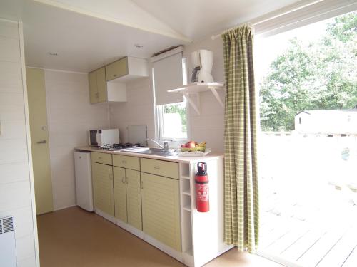 a kitchen with green cabinets and a window at Camping La Pindière in Héric