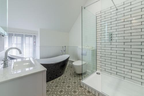 a bathroom with a tub and a toilet and a sink at No33 THORNHAM BOUTIQUE COTTAGE 2 in Thornham