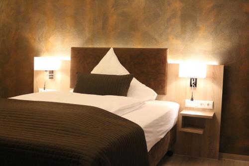 a bedroom with a large bed with two lamps at Hotel Baldus in Delmenhorst
