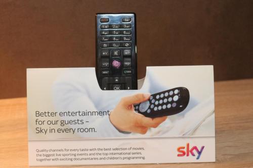 a hand holding a remote control on a box at Hotel Baldus in Delmenhorst