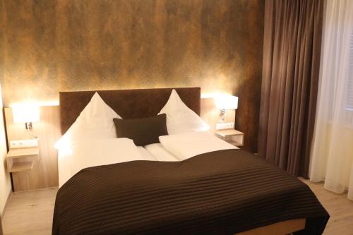 a bedroom with a black and white bed with two lamps at Hotel Baldus in Delmenhorst