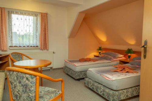 a room with two beds and a table and chairs at Pension zum Schwanenteich in Neuhaldensleben