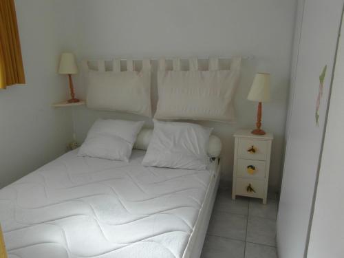 - un lit avec des draps et des oreillers blancs et 2 lampes dans l'établissement Résidence Hameau du Soleil, à Valras-Plage
