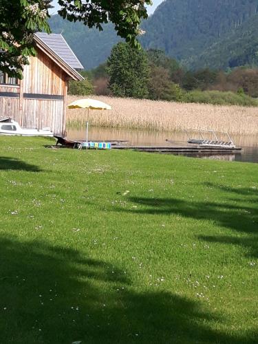 a house with an umbrella next to a body of water at Ferienhaus Silja in Steindorf am Ossiacher See