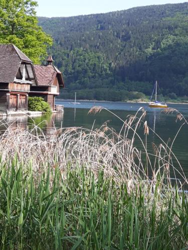 a house on a lake with a sail boat in the water at Ferienhaus Silja in Steindorf am Ossiacher See