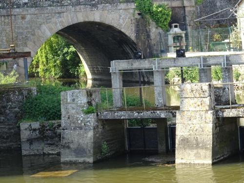 an old stone bridge over a river with murky water at Mahe in Plancoët