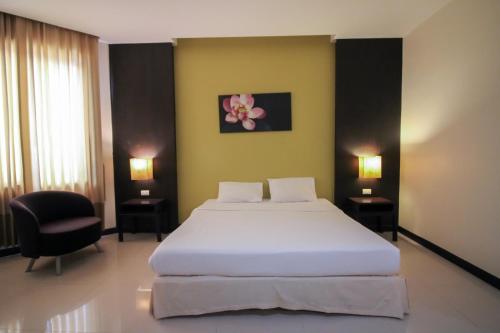 a bedroom with a large white bed and a chair at Jumbo House in Tha Sae