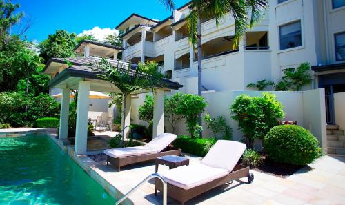 a pool with two chairs and a gazebo next to a building at Portside Whitsunday Luxury Holiday Apartments in Airlie Beach