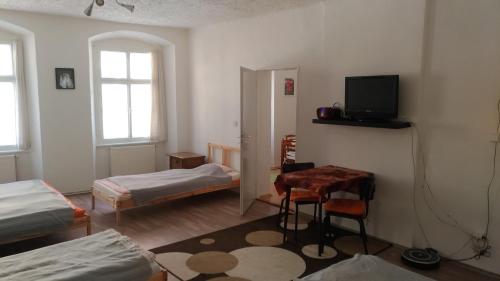 Cette chambre comprend deux lits, une table et une télévision. dans l'établissement Skromný apartmán v centru Chebu, à Egra